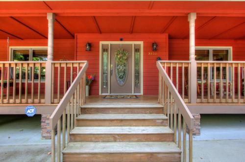 un porche delantero de una casa roja con escaleras en Gorgeous "Country Roads" by HoneyBearCabins 4BR 4BA, next to pool, easy drive, main strip location!, en Pigeon Forge