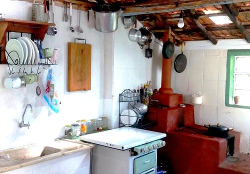een keuken met een rode kachel en een wastafel bij Simplicidade - Uma autêntica casa de roça mineira in Delfim Moreira