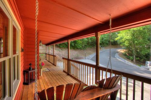 a porch with two chairs and a swing at Gorgeous "Country Roads" by HoneyBearCabins 4BR 4BA, next to pool, easy drive, main strip location! in Pigeon Forge