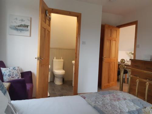 a bedroom with a bed and a bathroom with a toilet at An Cois Na H-Aibhne in Skeabost