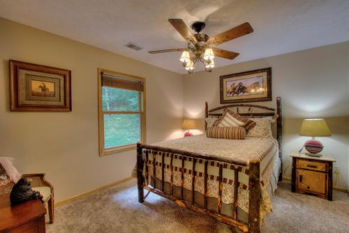 a bedroom with a bed and a ceiling fan at Gorgeous "Country Roads" by HoneyBearCabins 4BR 4BA, next to pool, easy drive, main strip location! in Pigeon Forge