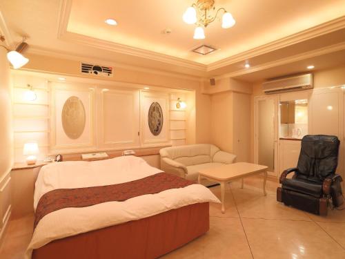 a bedroom with a bed and a chair and a table at Hotel Fine Garden Kuwana in Kawagoe
