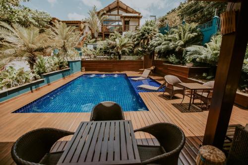 a swimming pool with a table and chairs next to it at Pousada Alto da Pipa in Pipa