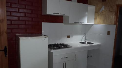 a white kitchen with a sink and a stove at Cabañas Claire in El Quisco