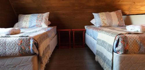 a room with two beds with blankets and pillows at Cabañas El Desván in Puente Negro