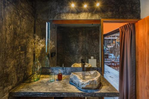 a bathroom with a stone sink and a mirror at Meteora Stay & Coffeehouse Tulum in Tulum