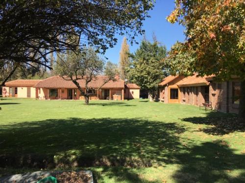 een huis in een tuin met een grote tuin met bomen bij Casa Los Ciervos in Pirque