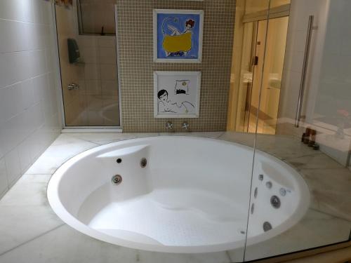 a white bath tub in a bathroom with a shower at A2 suites - Hotel e Motel in Brasilia