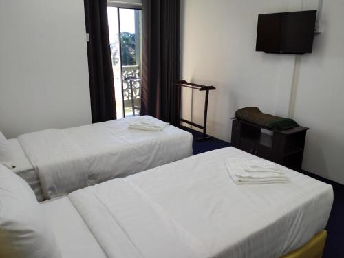 a hotel room with two beds and a television at MAIDAM Inn in Jertih