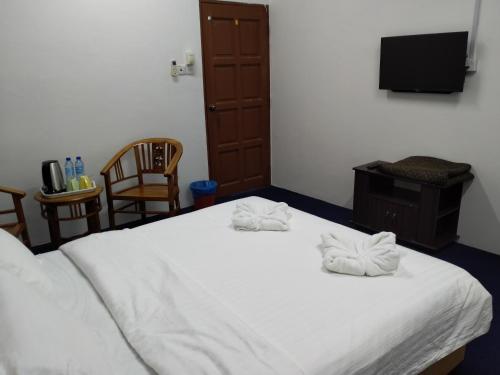 a bedroom with a white bed with towels on it at MAIDAM Inn in Jertih