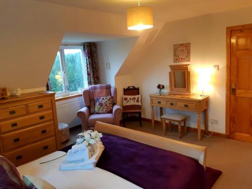 a living room with a bed and a chair and a desk at An Cois Na H-Aibhne in Skeabost