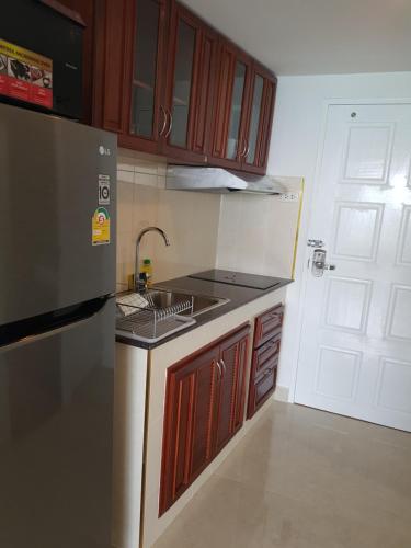 a kitchen with wooden cabinets and a sink and a refrigerator at Vip condo chain by Linda in Ban Phe