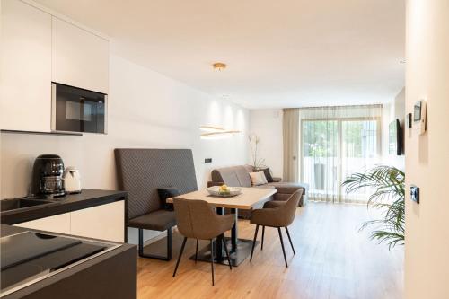 a kitchen and a living room with a table and chairs at Nice Living Neue- Moderne Apartments im Herzen von Brixen - kostenlose Brixencard - ideal für Familien, Paare, Geschäftsreisende, Gäste mit Hund und allen Urlaubs Hungrigen in Bressanone