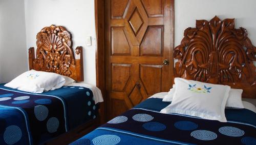 1 dormitorio con 2 camas y puerta de madera en Posada y Spa Jade Teotihuacan, en San Juan Teotihuacán