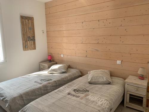 two beds in a room with wooden walls at La petite rétaise in La Flotte