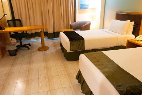 a hotel room with two beds and a desk and a table at Holiday Inn Dar Es Salaam by IHG in Dar es Salaam
