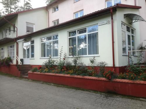 a white house with flowers in front of it at Svečių namai ALDAIVITA in Ignalina