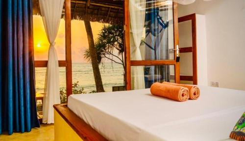 a bedroom with a bed with a view of the ocean at Mnana Beach Bungalows in Michamvi