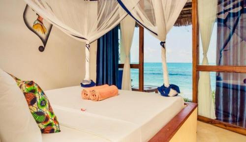 a bed in a room with a view of the ocean at Mnana Beach Bungalows in Michamvi
