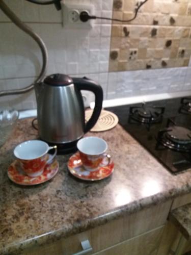 a tea kettle and two cups on a kitchen counter at Центрові апартаменти in Ivano-Frankivsʼk