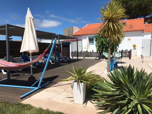 a patio with a hammock and an umbrella at Casa o Futuro in Alcobaça