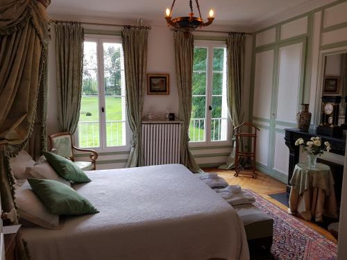 a bedroom with a large bed and windows at Château de Cleuville in Cleuville