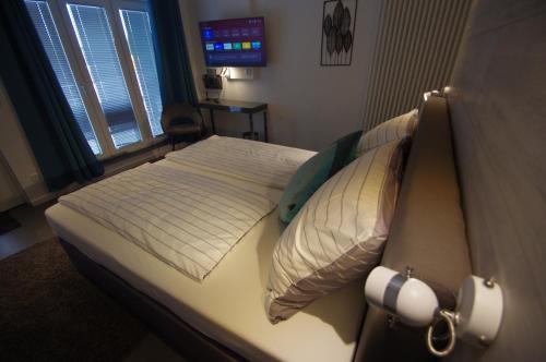a bedroom with a bed with white sheets and pillows at CityMotel Ziegenhain in Schwalmstadt