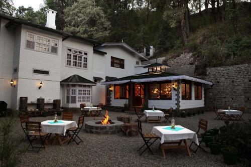 uma grande casa branca com mesas e uma fogueira em Bhikampur Lodge By Howard em Nainital