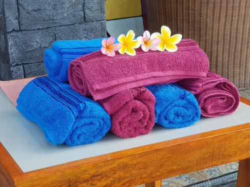 a pile of towels on a table with flowers on them at House of Belasun in Pelabuhan Ratu