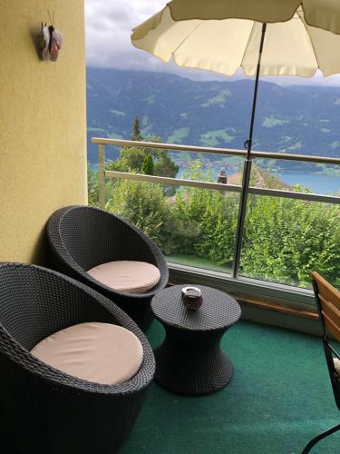 a balcony with chairs and an umbrella and a view at Wohnung mit See und Bergsicht im vier Sterne Hotel in Beatenberg