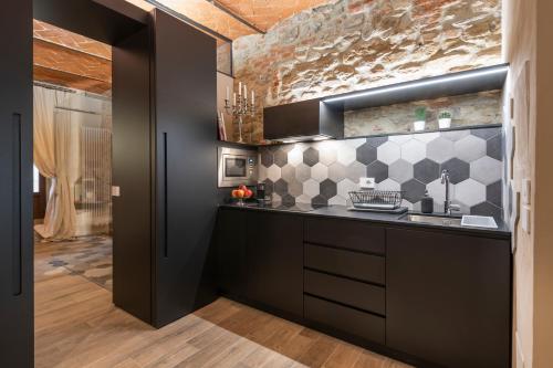 une cuisine avec des placards noirs et un mur en carrelage dans l'établissement Fioraia5 Dimora, à Arezzo