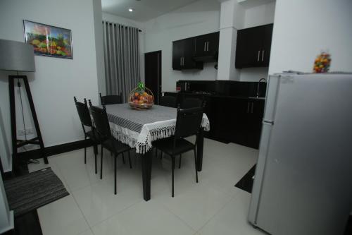 a kitchen with a table and chairs and a refrigerator at SkyCasa Holiday Apartments in Mount Lavinia