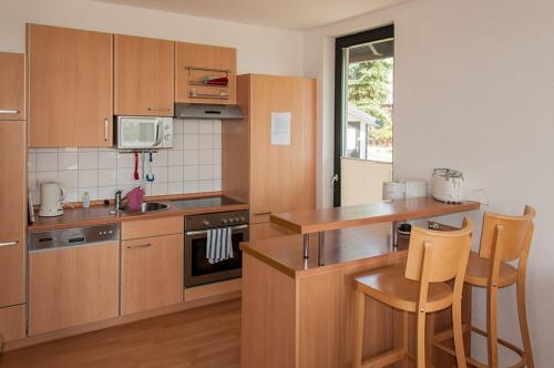 uma cozinha com armários de madeira e uma mesa e cadeiras em Ferienhaus Plau am See direkt am Strand em Plau am See