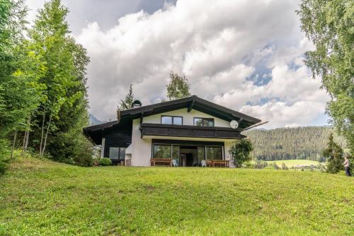 a house on a hill with a green lawn at Landhaus Blaubeerhügel in Ramsau am Dachstein