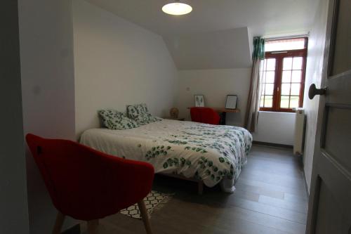 a bedroom with a bed and a red chair at Le gite des marcassins in Berlaimont
