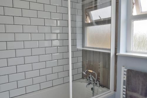 a bathroom with a shower with white subway tiles at Gwel Angarder in Perranporth