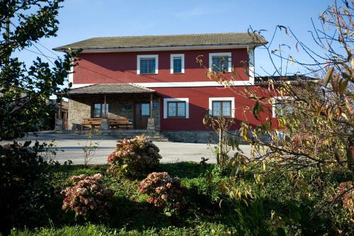 a large red house with a porch in front of it at Hotel Rural Suquin in Navia
