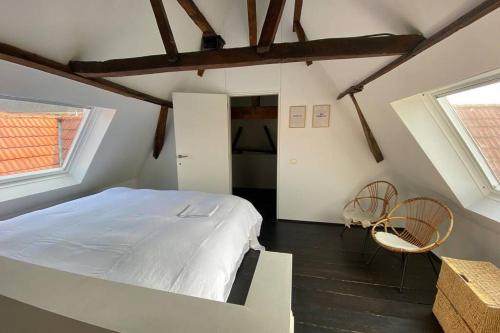 een slaapkamer met een wit bed en 2 stoelen bij GLORIA LOFT GENT in Gent