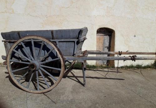 un carro de madera sentado frente a un edificio en Nid de Poussins, en Vaumeilh