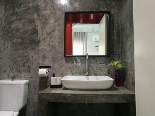ein Badezimmer mit einem Waschbecken, einem WC und einem Spiegel in der Unterkunft บ้าน guh (กูว์) in Uthai Thani