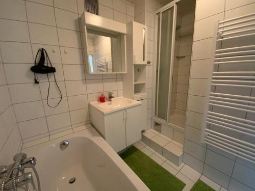 a white bathroom with a tub and a sink at Pension Lipicer in Kötschach