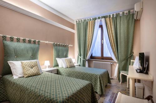 a hotel room with two beds and a window at La Dimora Delle Terme in Rapolano Terme