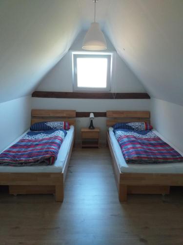 two beds in a attic room with a window at Lutzes Ferienhaus in Knittelsheim