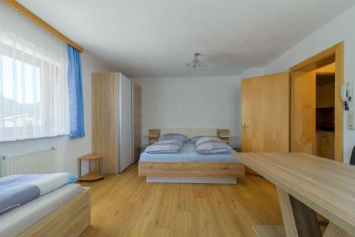 a bedroom with two beds and a wooden table at Haus Schimpfössel in Flirsch
