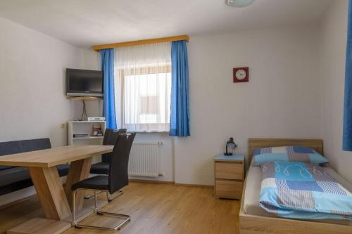1 dormitorio con cama, escritorio y mesa en Haus Schimpfössel en Flirsch