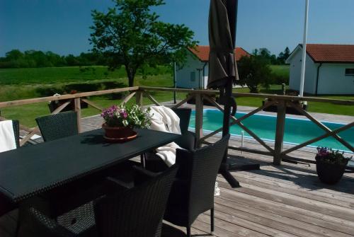 a wooden deck with a table and chairs and a pool at Nordanå Gård in Strö