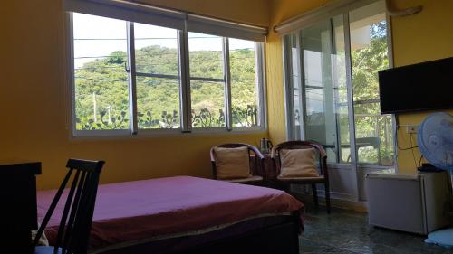 a bedroom with a bed and two chairs and windows at View Mountain B&B in Checheng
