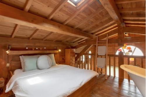 Un dormitorio con una cama blanca en una habitación con techos de madera. en L'Esprit Montpel "La Cabane-Chalet de Montagne", en Vendargues