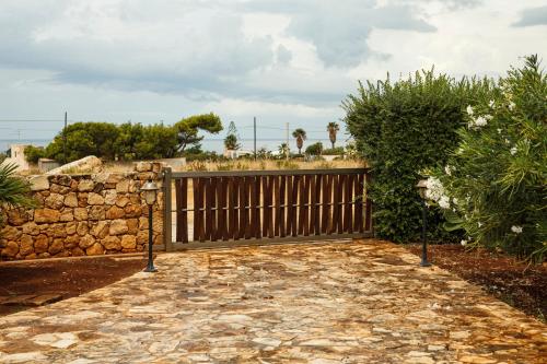 un cancello in legno con una recinzione in pietra e un muro in pietra di Cornino Bay a Custonaci