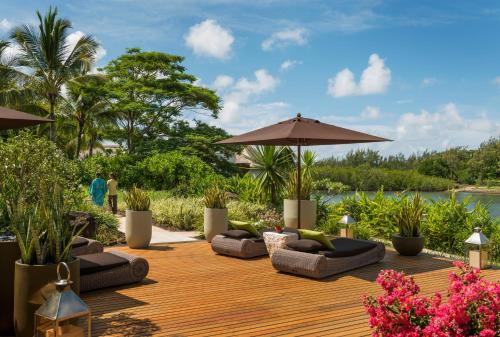 a wooden deck with couches and an umbrella at Four Seasons Resort Mauritius at Anahita in Beau Champ